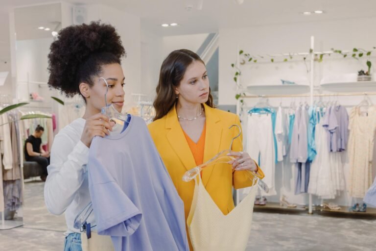 Two stylish women picking outfits together in a trendy clothing store.